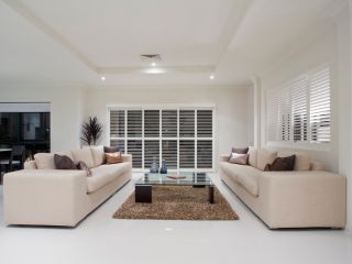 Sunlight filtering through horizontal mini blinds, casting elegant shadows on the floor and adding a warm touch to the interior decor.