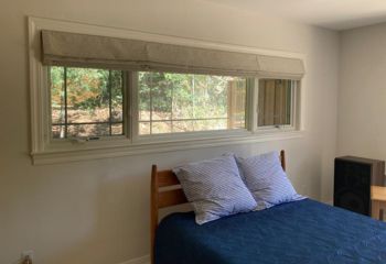 Wide bedroom window in Walnut Creek fitted with stylish custom Roman shades featuring a subtle print, partially lowered for filtered daylight.