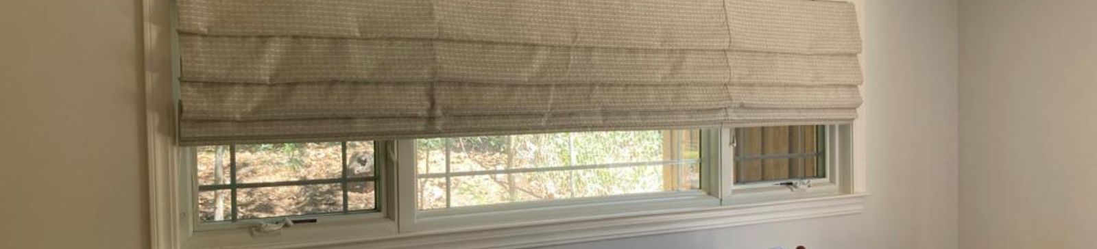 Walnut Creek bedroom window with custom Roman blinds partly raised, letting in natural light and showcasing the room’s welcoming décor.