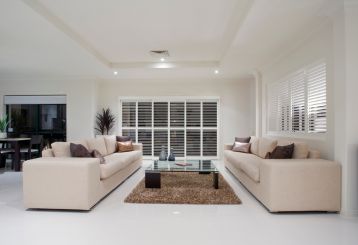 Sunlight filtering through horizontal mini blinds, casting elegant shadows on the floor and adding a warm touch to the interior decor.